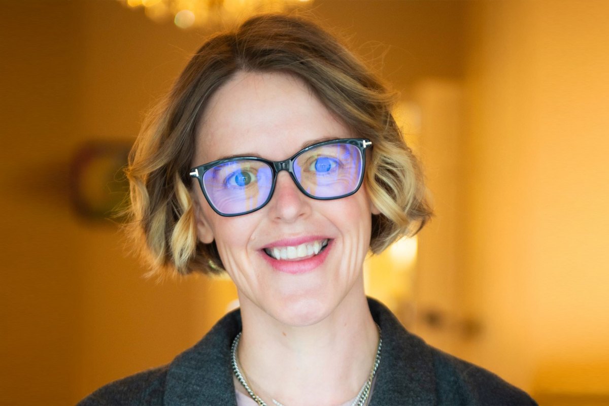 Headshot of Lauren Stokes, in glasses, in a warm toned room