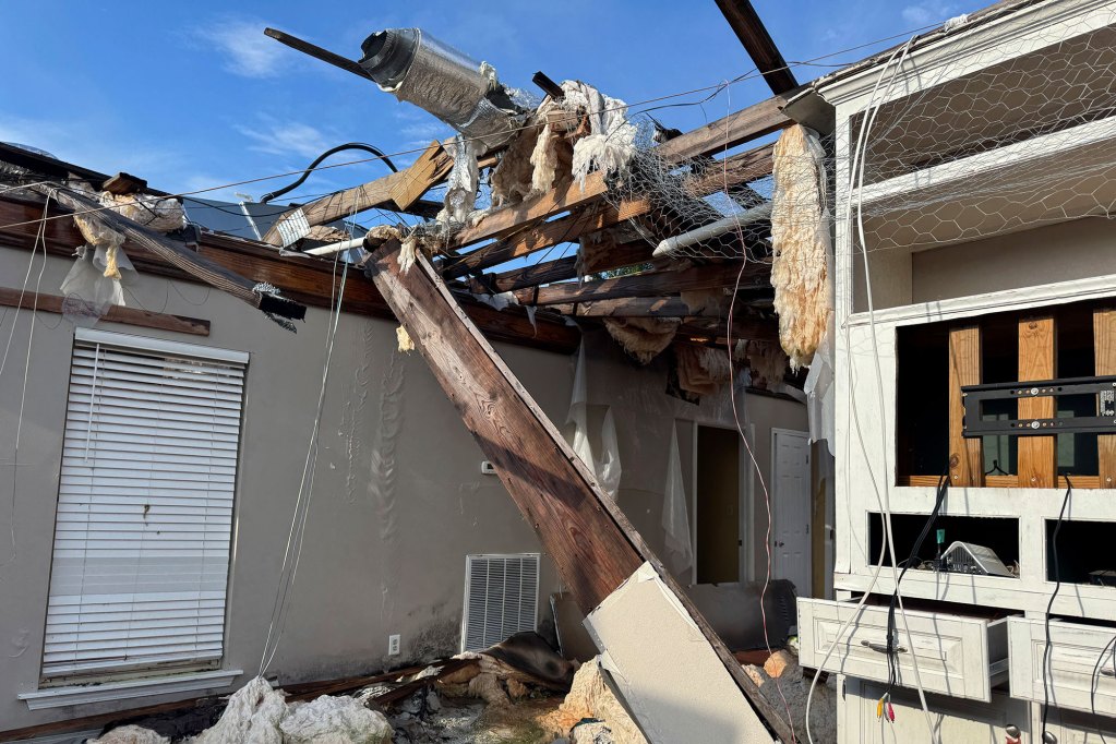 An interior view of a tornado damaged home, blue sky visible where the roof should be