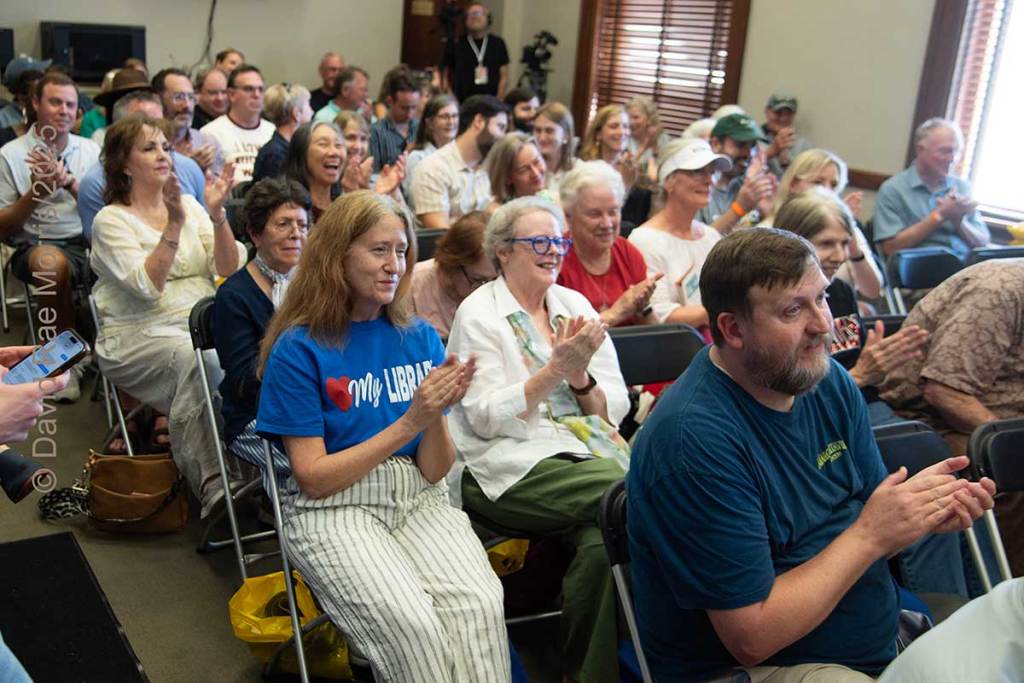 An audience in a book panel seen clapping