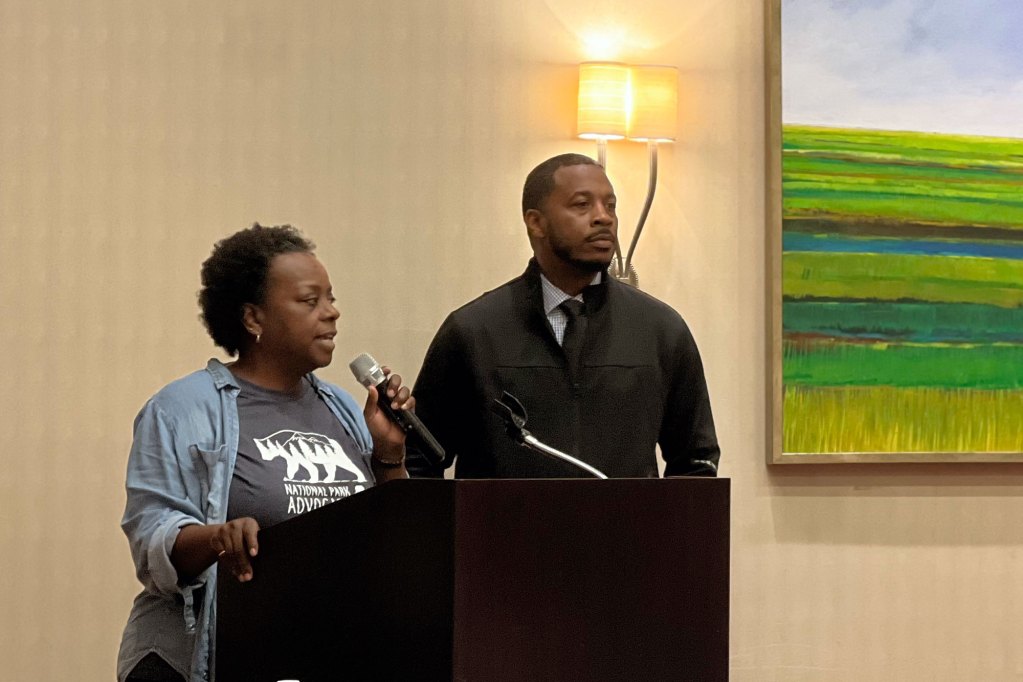Two people speak at a podium inside a room