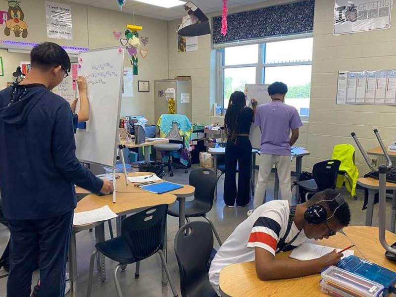 Students work on projects at different desks in a classroom