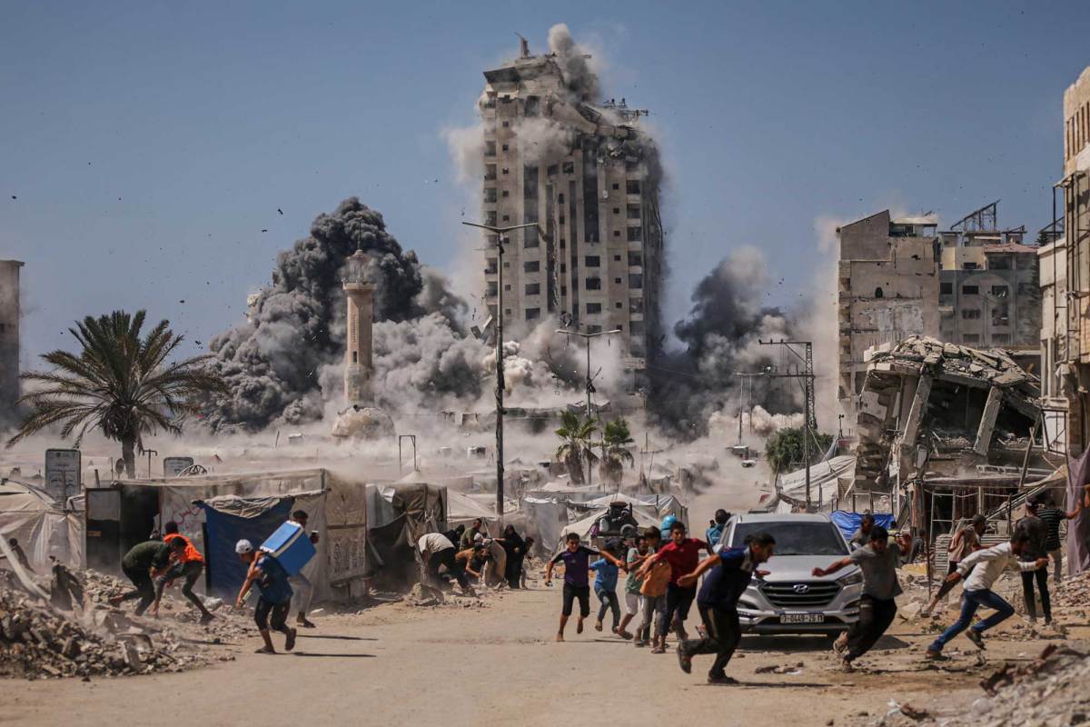 Palestinians run as bombs hit buildings behind them
