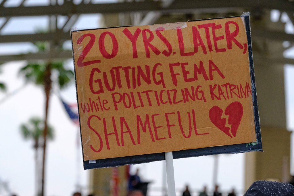 A sign that reads '20 Yrs. Later, Gutting FEMA while Politicizing Katrina SHAMEFUL'