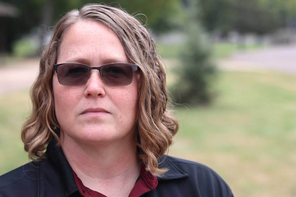A woman in sunglasses stands outside