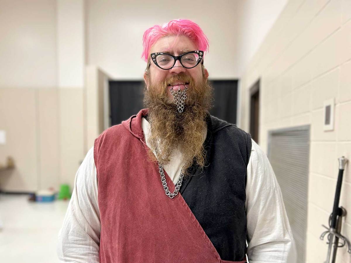 A person with pink and brown hair and chainmail hanging from their lip