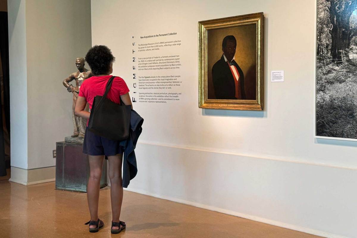 A woman looks at a painted portrait of Frederick in a museum