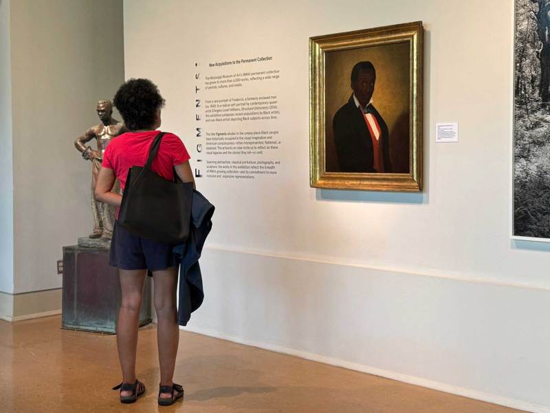 A woman looks at a painted portrait of Frederick in a museum