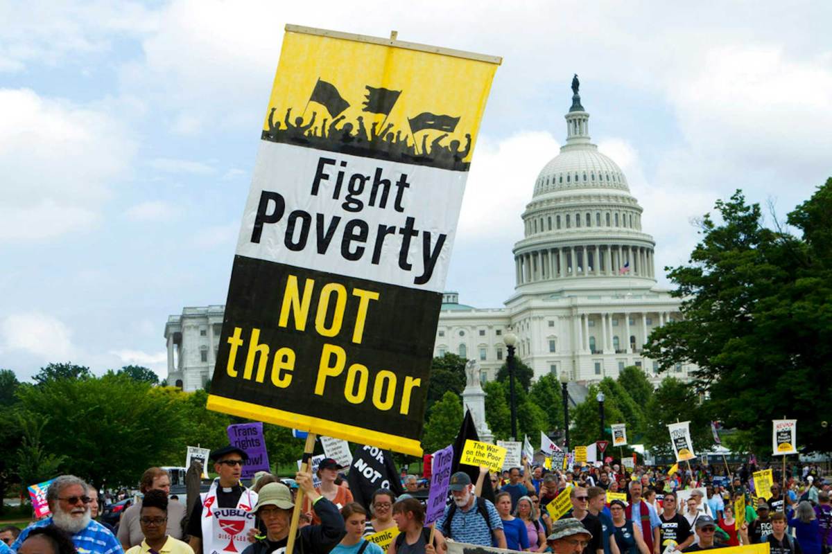 A sign that reads, “Fight Poverty, Not the Poor,” is held at a protest.