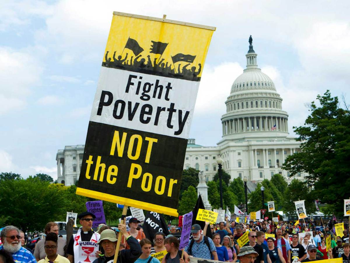 A sign that reads, “Fight Poverty, Not the Poor,” is held at a protest.