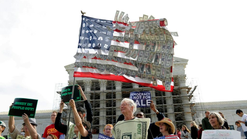Demonstrators hold an American flag covered in dollar bills during a protest.