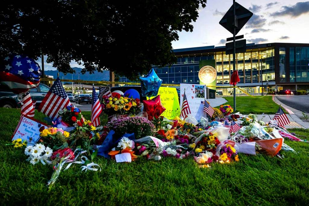 Brightly colored flowers, flags and balloons lying on the grass in front of a building