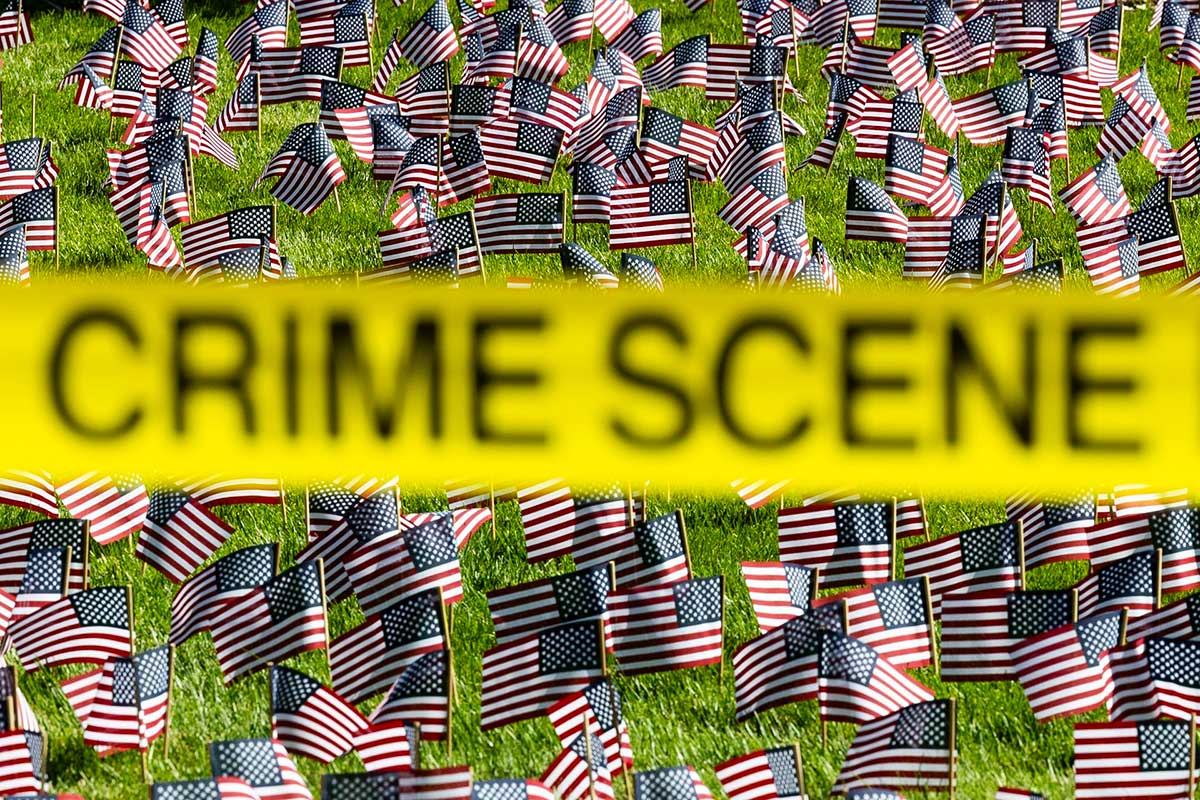A lawn covered in small US Flags is blocked by a yellow CRIME SCENE banner