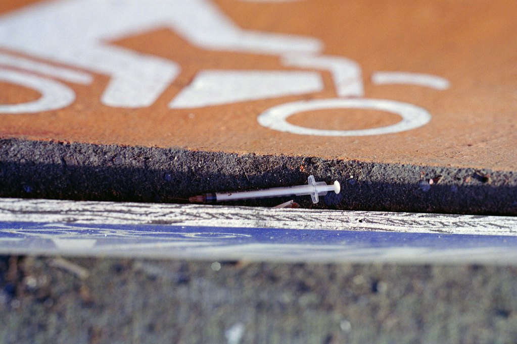 A syringe lies within a crack of a sidewalk