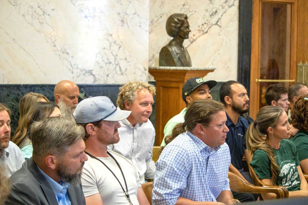 A group of people sit and listen to a meeting