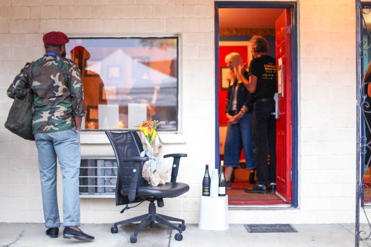 A man looking into a hotel room window at the art hanging within
