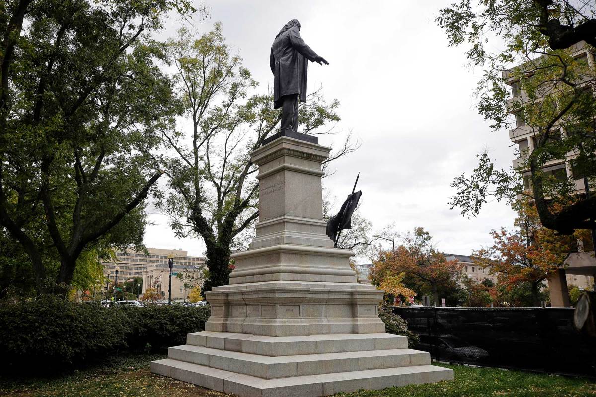 A confederate statue of a man on a tall pedestal located in a park