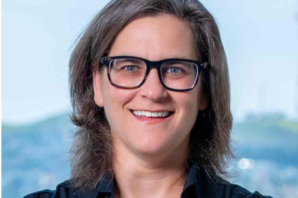 An official portrait of a woman with black glasses and shoulder length hair