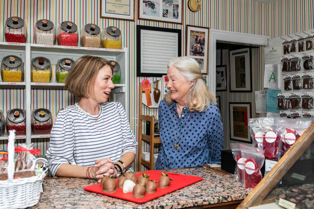 Emmie and Nancy King stand together behind the counter of their candy store