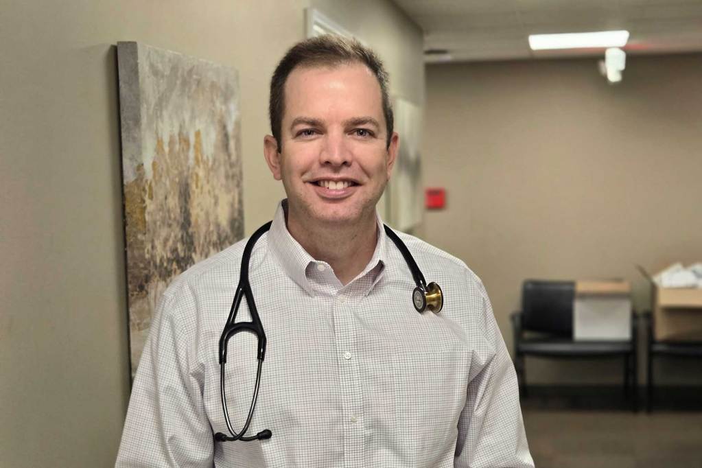 A white man with a stethoscope around his neck standing.