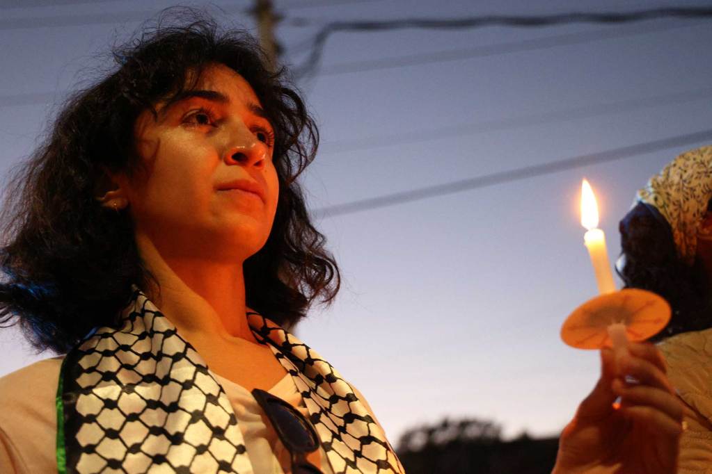 A woman holds a candle at a vigil