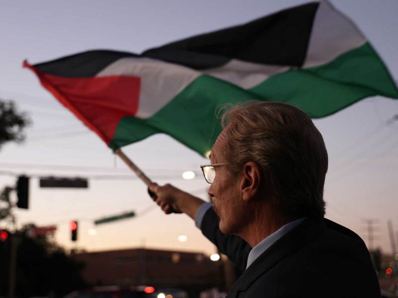 A man waves the Palestine flag at dusk
