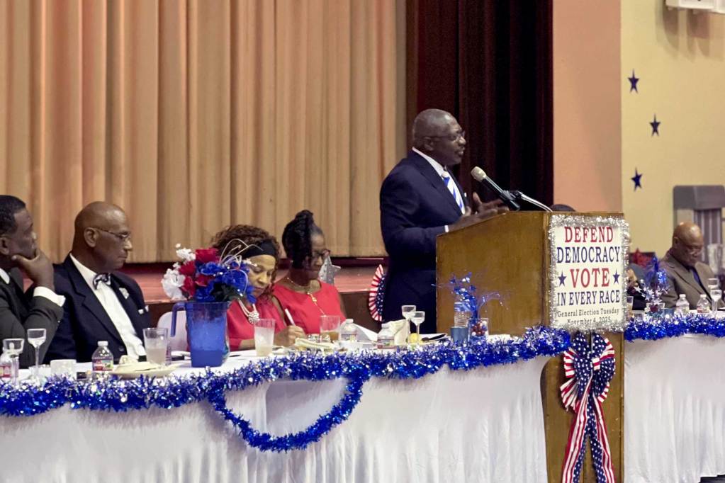 John Horhn speaks at an event, the podium before him reads 'Defend Democracy, Vote in Every Race'