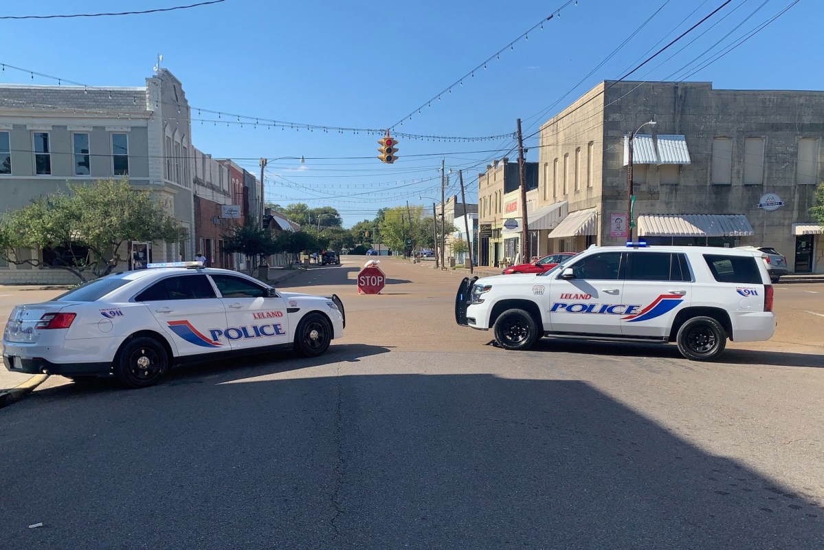 Two police cars parked next to each other in the middle of a four-way intersection.