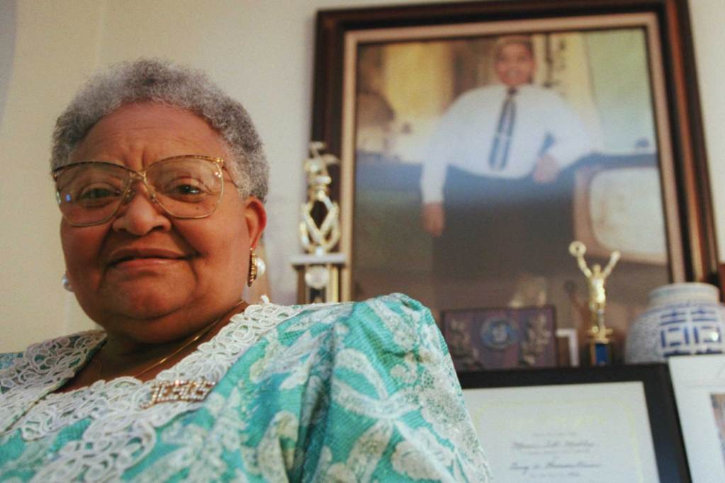 Mamie Till Mobley sits in her home in front of a hanging photo of her son Emmett Till