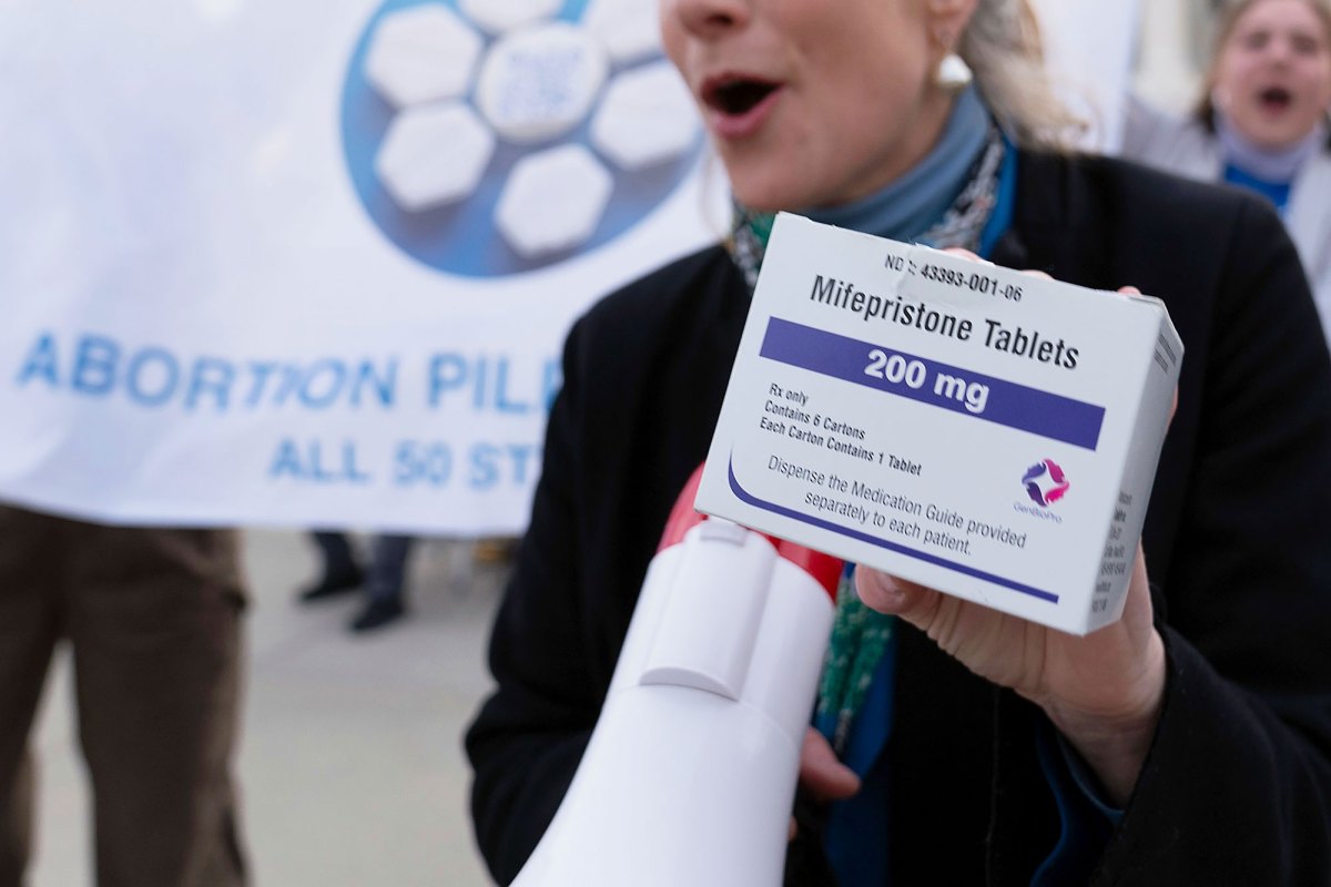 A hand holds up a box of Mifepristone Tablets
