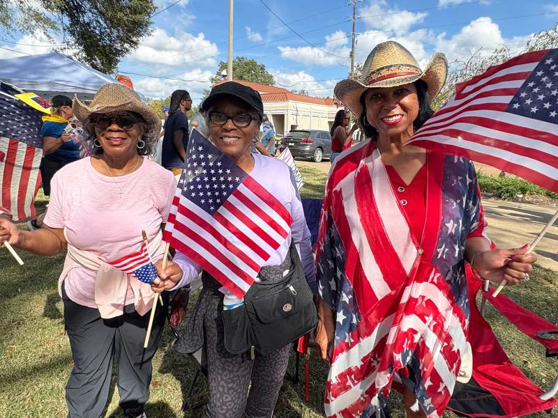 Three women waving US flags at a rally