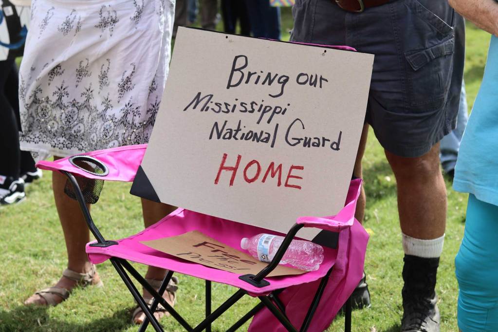 Protester sign sitting in a pink camper chair at a rally that reads 'Bring our Mississippi National Guard HOME'
