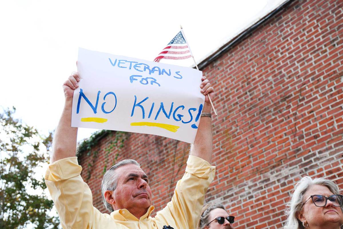 A man holds up a US Flag and a sign that reads 'Veterans for No Kings!'