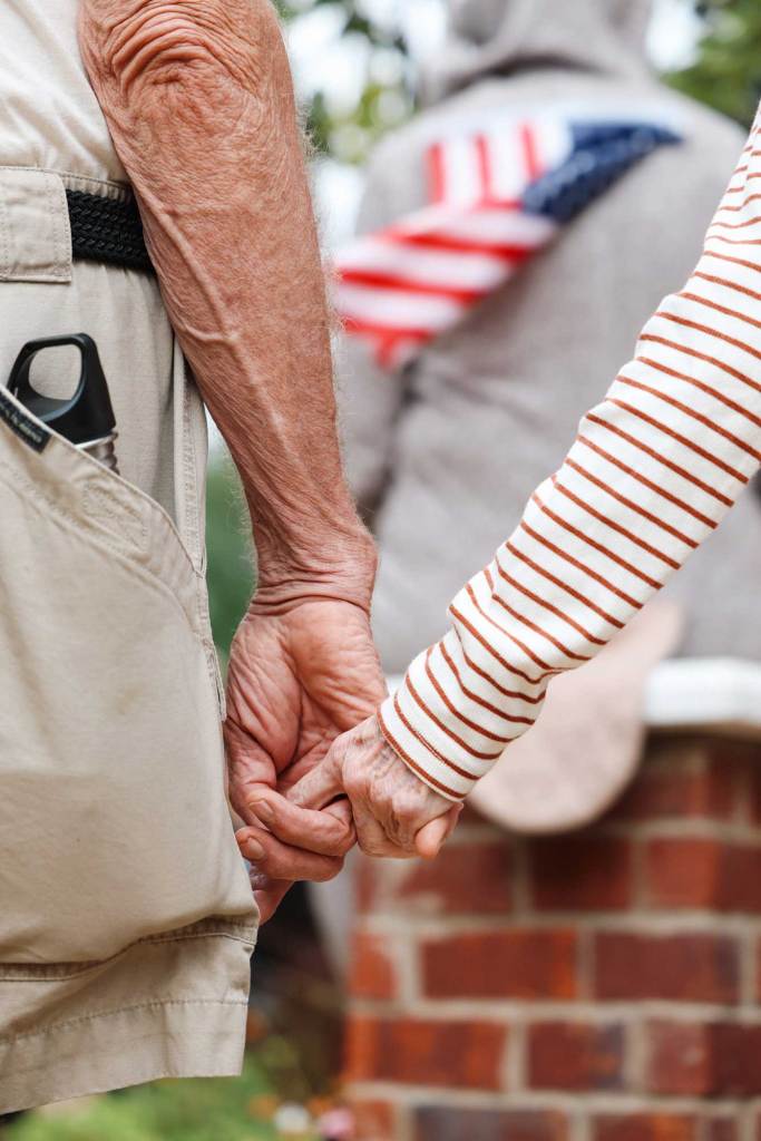 A closeup of two older people holding hands at a rally