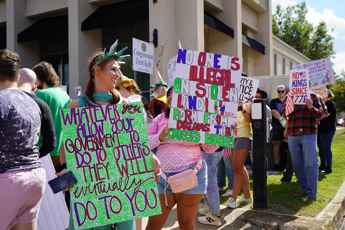 Protesters at a rally hold many signs. A woman dressed as the statue of liberty holds one that reads ' Whatever you allow your government to do to others they will eventually do to you'