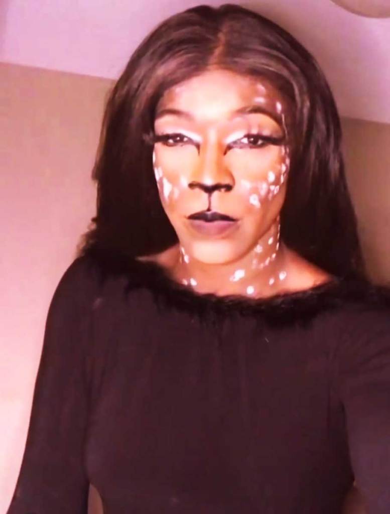 A woman wearing a dark shirt with colorful makeup on her face.