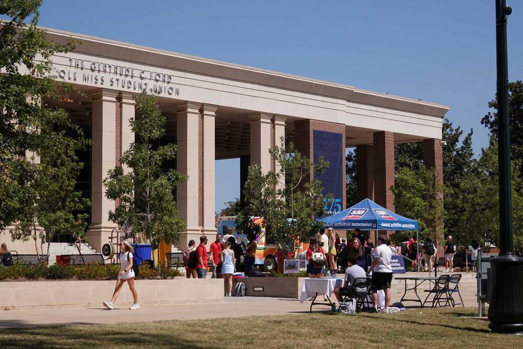 Students walk around and talk in front of a building labeled 'The Gertrude C Ford Ole Miss Student Union'