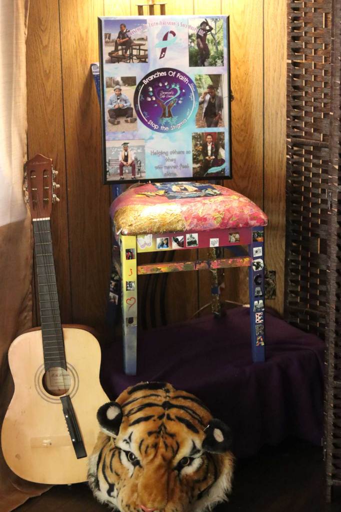 A display of a chair holding photos, with a guitar and a tiger head beside them
