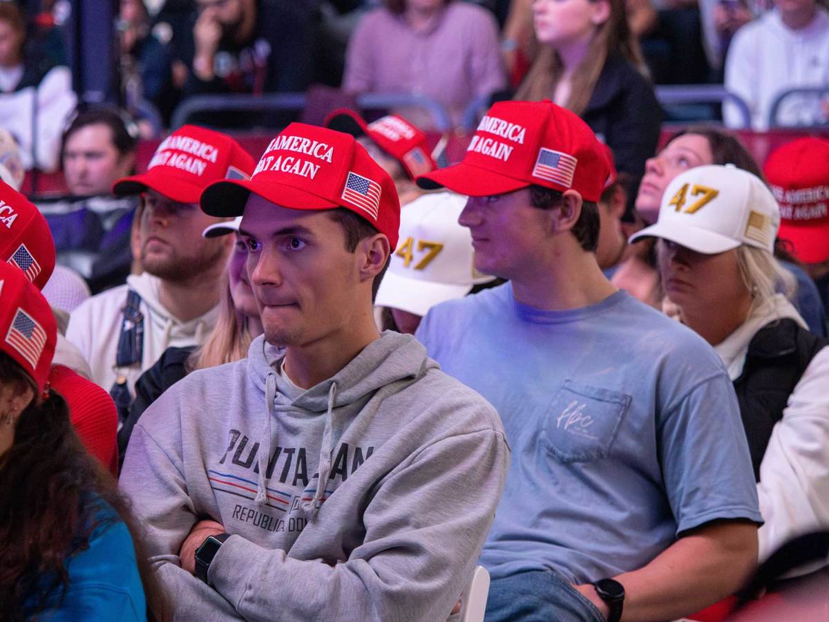 Young people wearing red ‘Make America Great Again’ and white ‘47’ hats sitting in chairs on the floor of the John and Sandy Black Pavilion at the University of Mississippi.