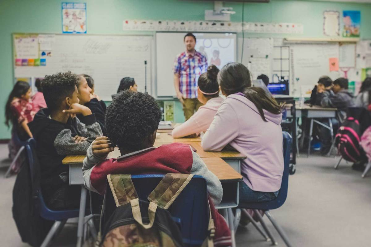A classroom where students sit around tables in groups and look forward towards the teacher