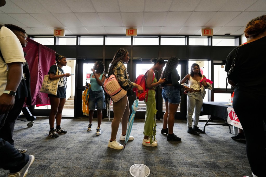 a group of black college students stand in a line outside a door with exit signs
