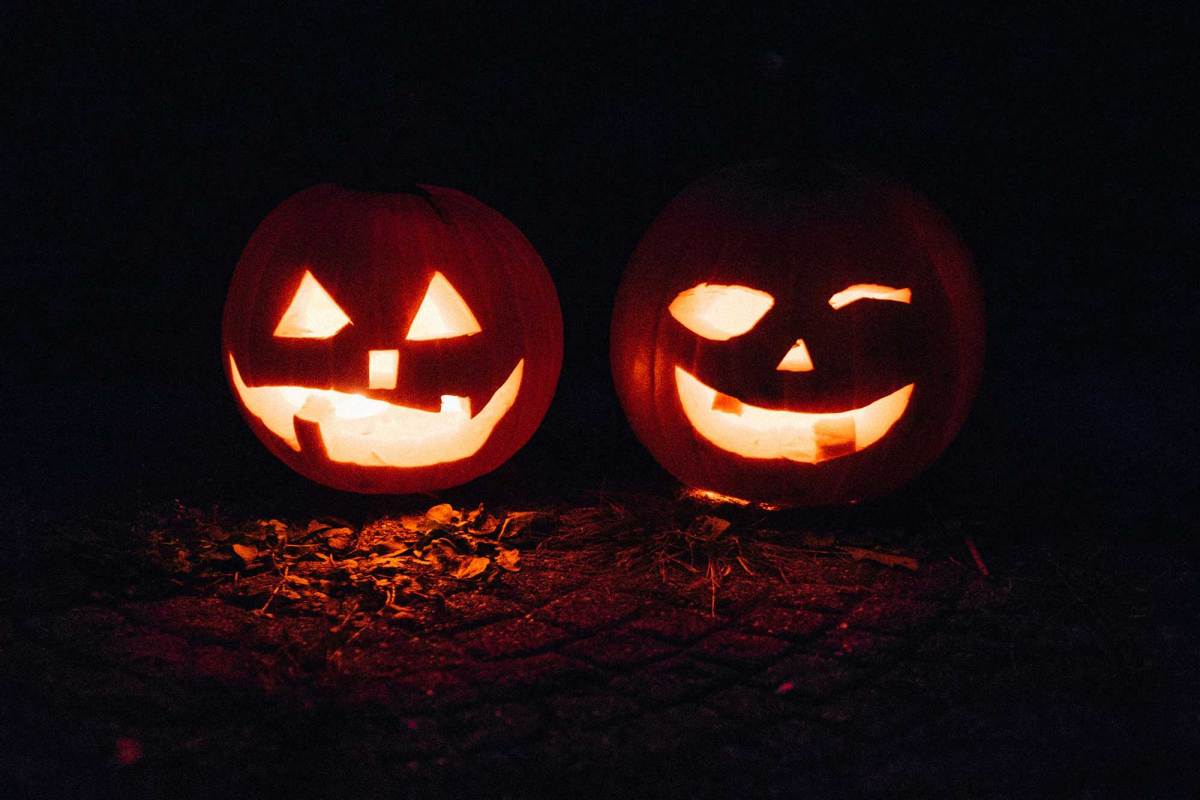 Two jack-o-lanterns lit against dark surroundings.