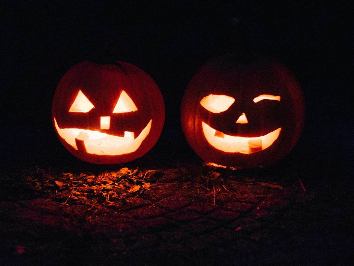 Two jack-o-lanterns lit against dark surroundings.