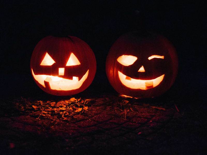 Two jack-o-lanterns lit against dark surroundings.
