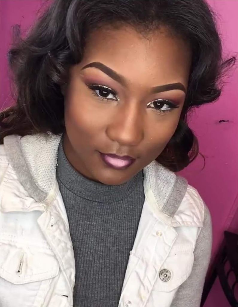 A selfie of a woman against a pink wall