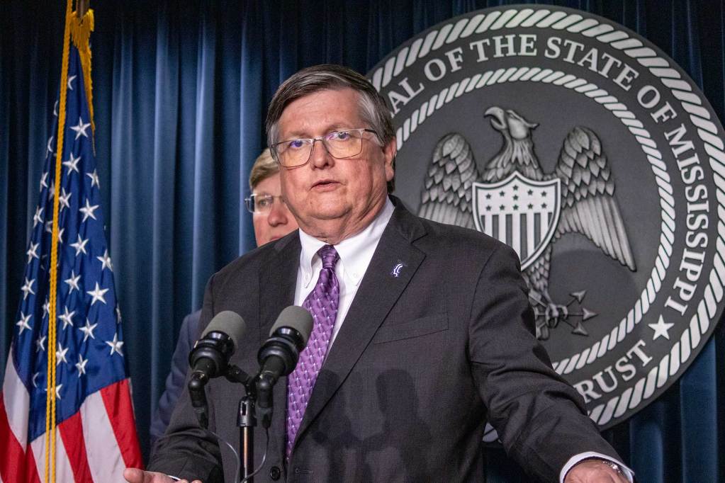 Dan Edney speaking in front of the seal of Mississippi at a press conference
