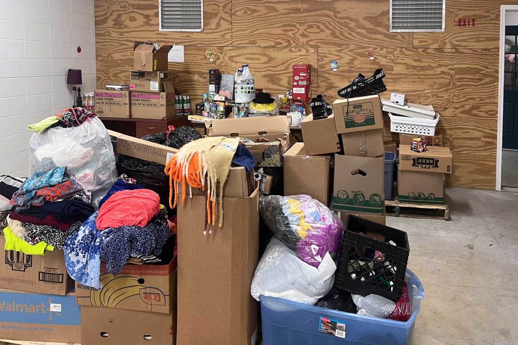 Boxes of donated clothes and other items sit on neat pallets in a room