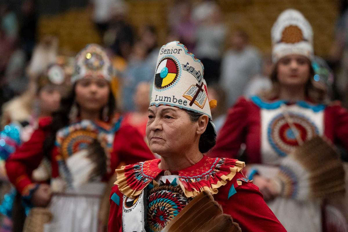 A view of indigenous peoples in traditional dress, mainly in red and white colors with intricate beadwork headdresses