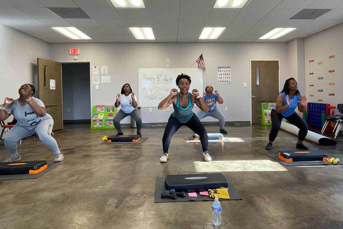Five women in a room do squatting exercises