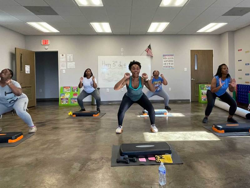 Five women in a room do squatting exercises