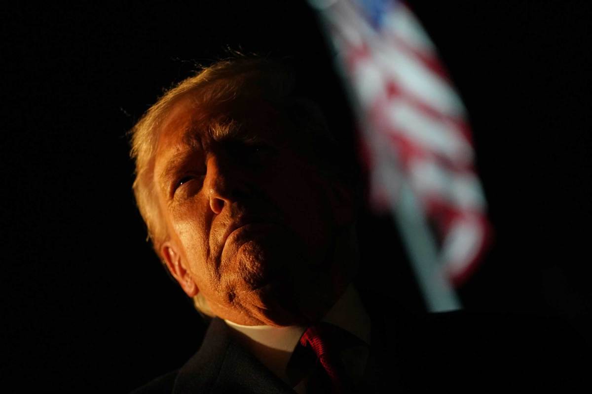 Donald Trump outside at night, dramatically lit on one side of his face only